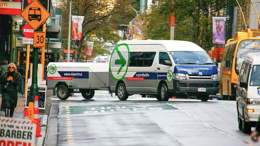 Super Shuttle van on city street for airport transfers.