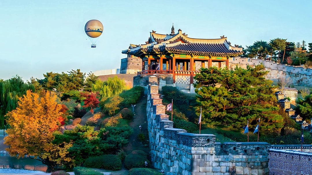 Hot air balloon over Suwon Hwaseong Fortress with autumn trees, part of Korean Folk Village tour.