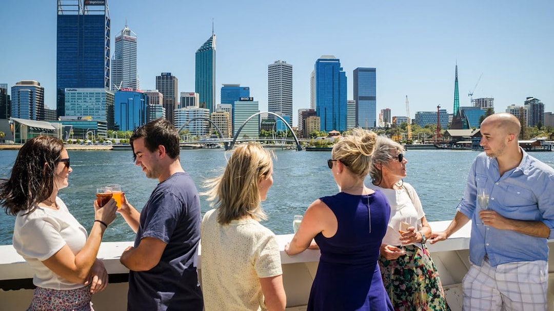 Cruise guests enjoying drinks with Perth skyline in the background.