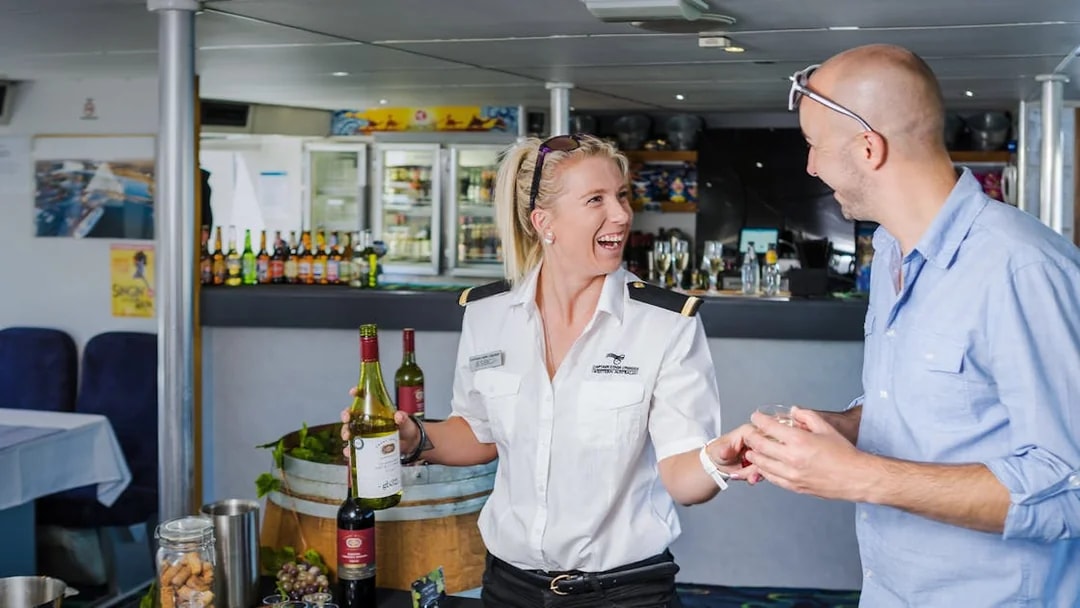 Server offering wine to a guest on a Swan River dining cruise.