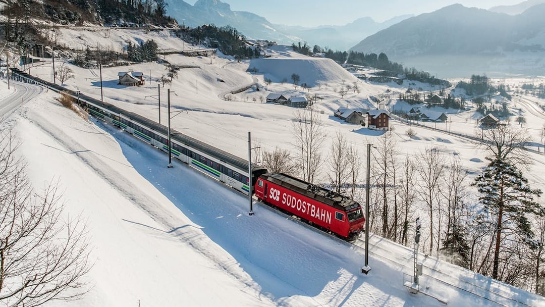 Train traveling through snowy Swiss Alps landscape with Swiss Travel Pass.