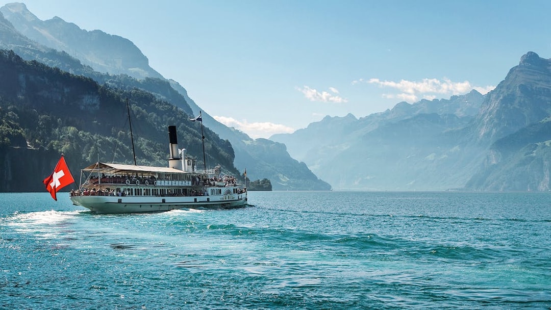 Steamboat on Lake Brienz with Swiss flag, surrounded by mountains in Berner Oberland.