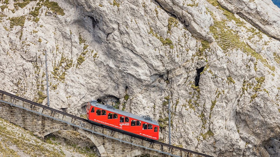 Red cogwheel train ascending Mount Pilatus in Lucerne, part of the Swiss Travel System.
