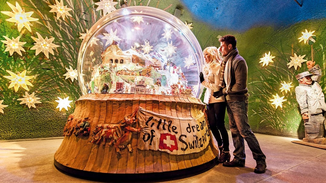 Couple admiring a large snow globe display at a museum in Jungfraujoch, Switzerland.
