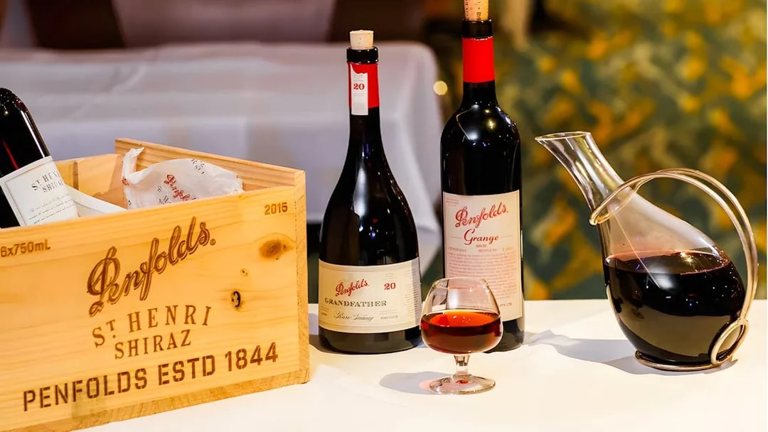 Penfolds wine bottles and decanter with wooden crate on display.