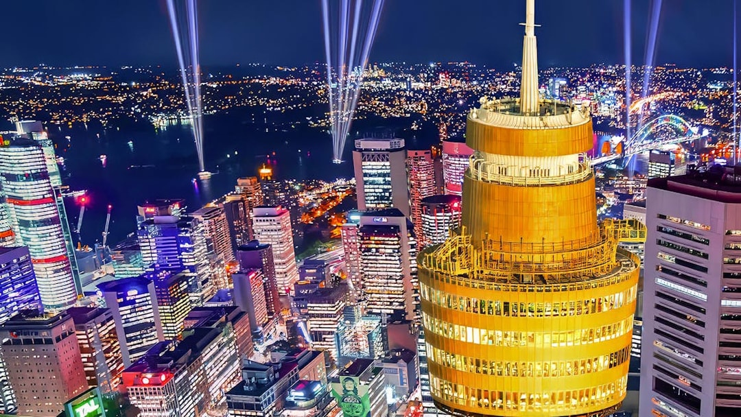 Sydney skyline at night featuring illuminated Sydney Tower and city lights.