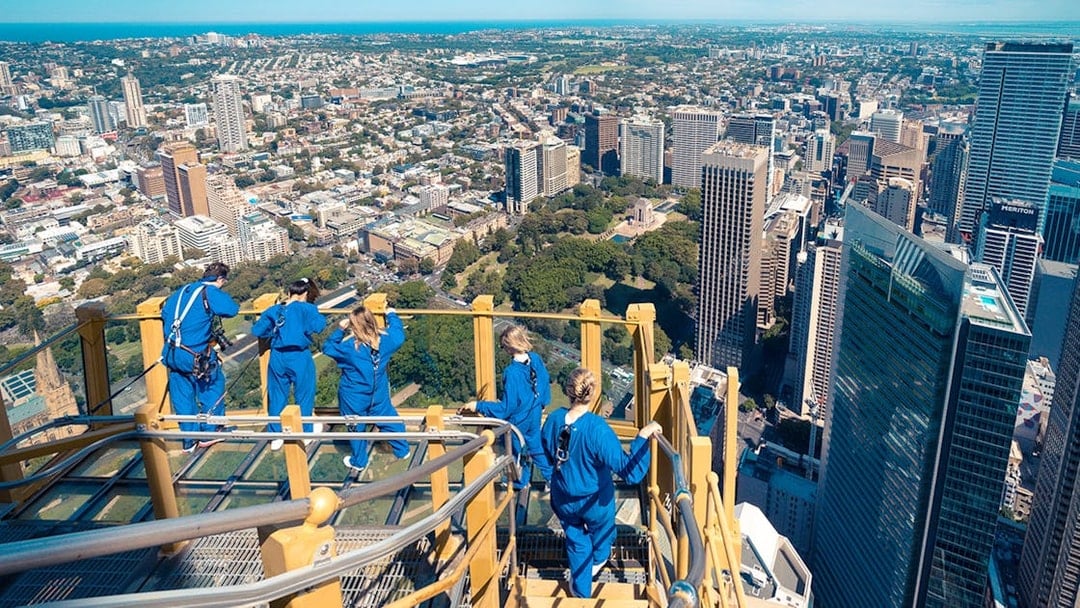 Visitors on Skywalk at Sydney Tower Eye overlooking cityscape.