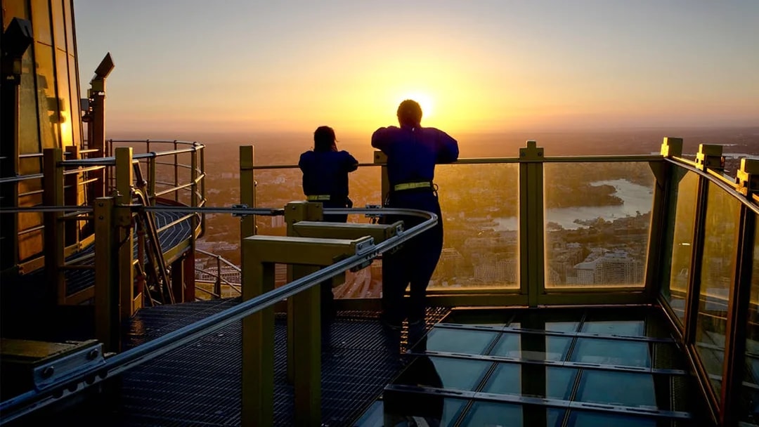 Visitors on Skywalk at Sydney Tower Eye enjoying city view at sunset.