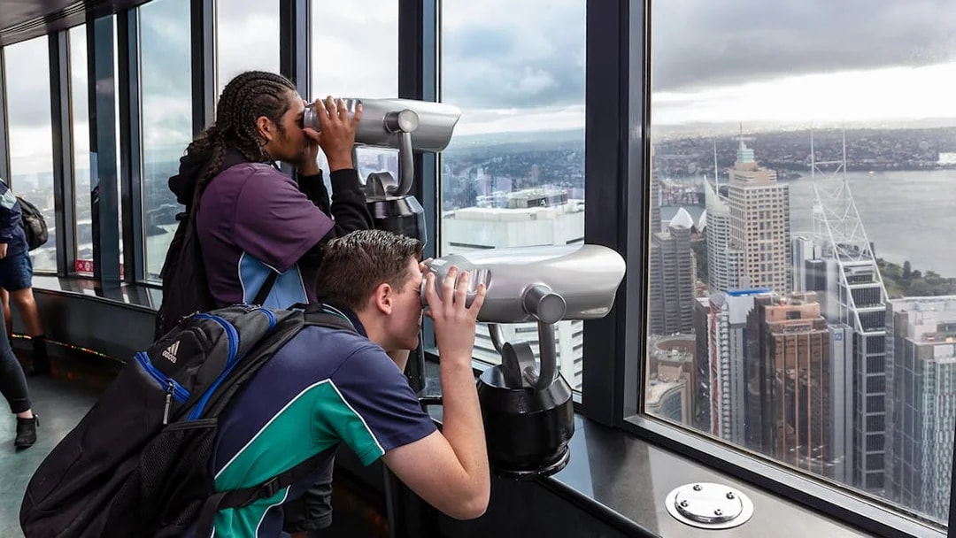Visitors using binoculars on Sydney Tower Eye observation deck.