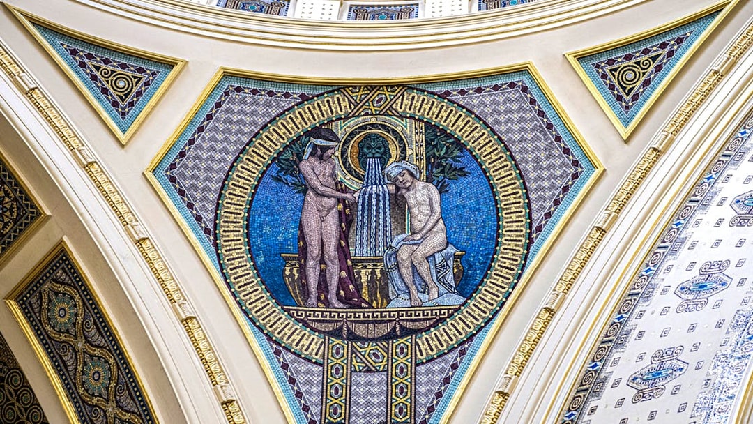 Mosaic artwork on Széchenyi Spa wall, Budapest, depicting classical figures and fountain.