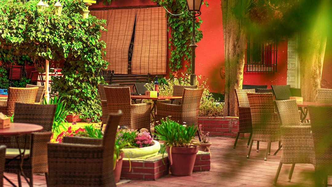 Outdoor seating area at Tablao flamenco Jardines de Zoraya with wicker chairs and lush greenery.