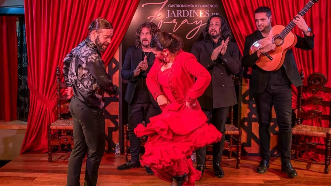 Flamenco dancers performing at Tablao Jardines de Zoraya with musicians in the background.