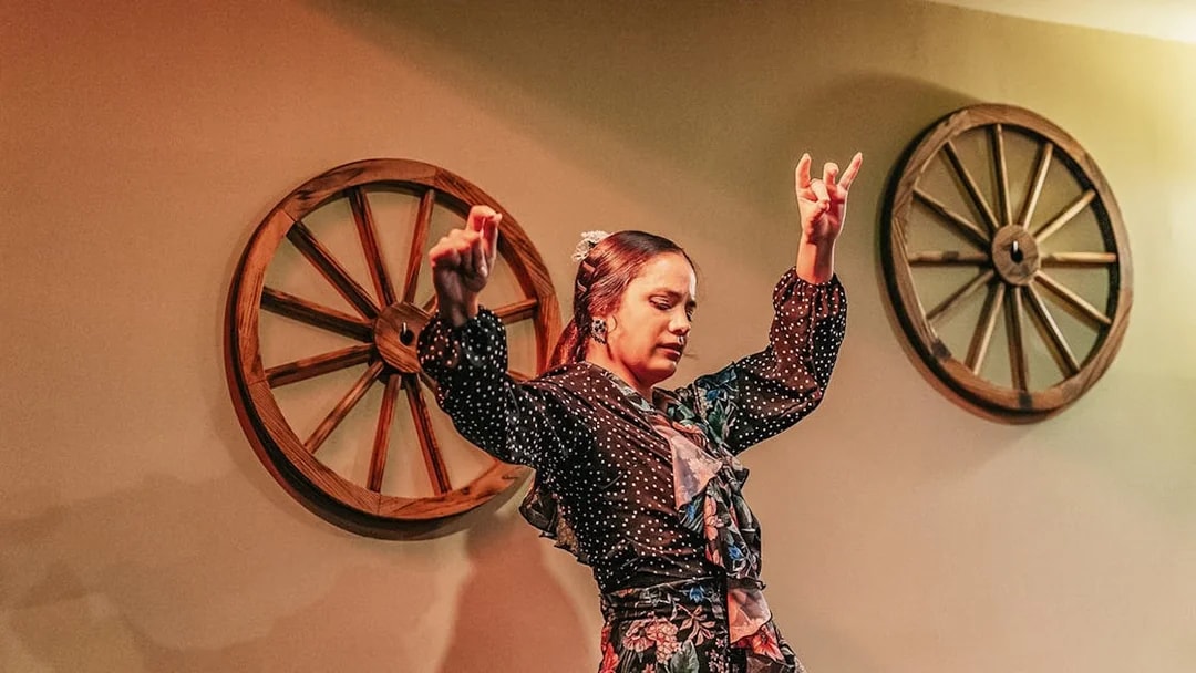 Flamenco dancer performing at a show with wooden wheel decor.