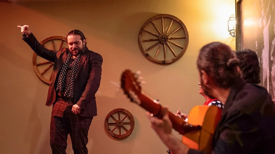 Flamenco dancer performing at Tablao La Cantaora in Seville with guitarist in foreground.