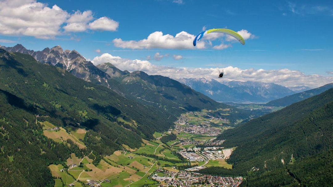 Tandem paragliding over scenic valley and mountains in Tirol, Austria.