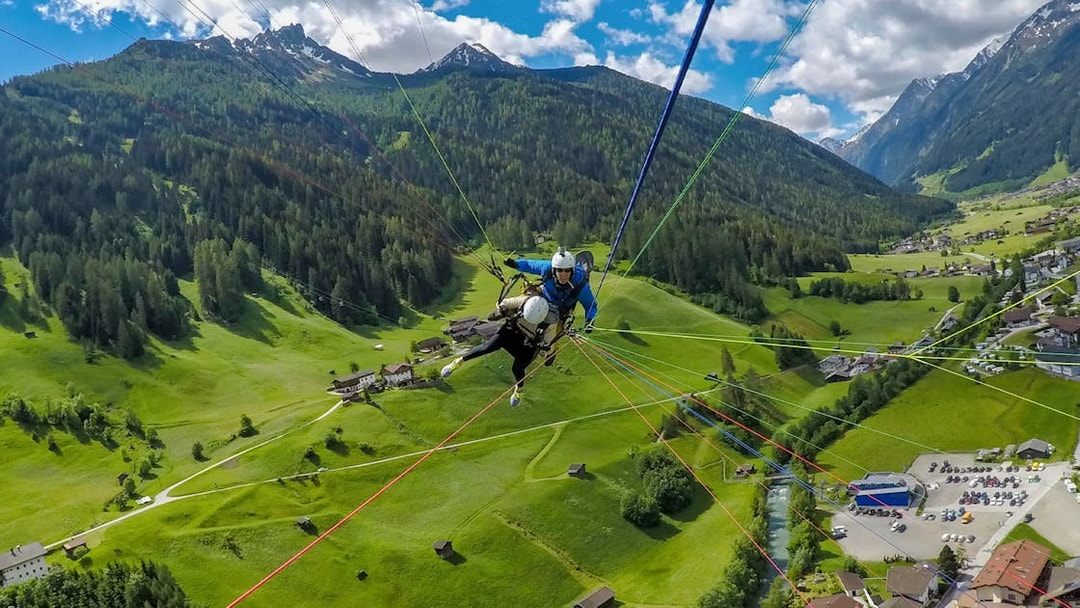 Tandem paragliding over green valleys and mountains in Tirol, Austria.