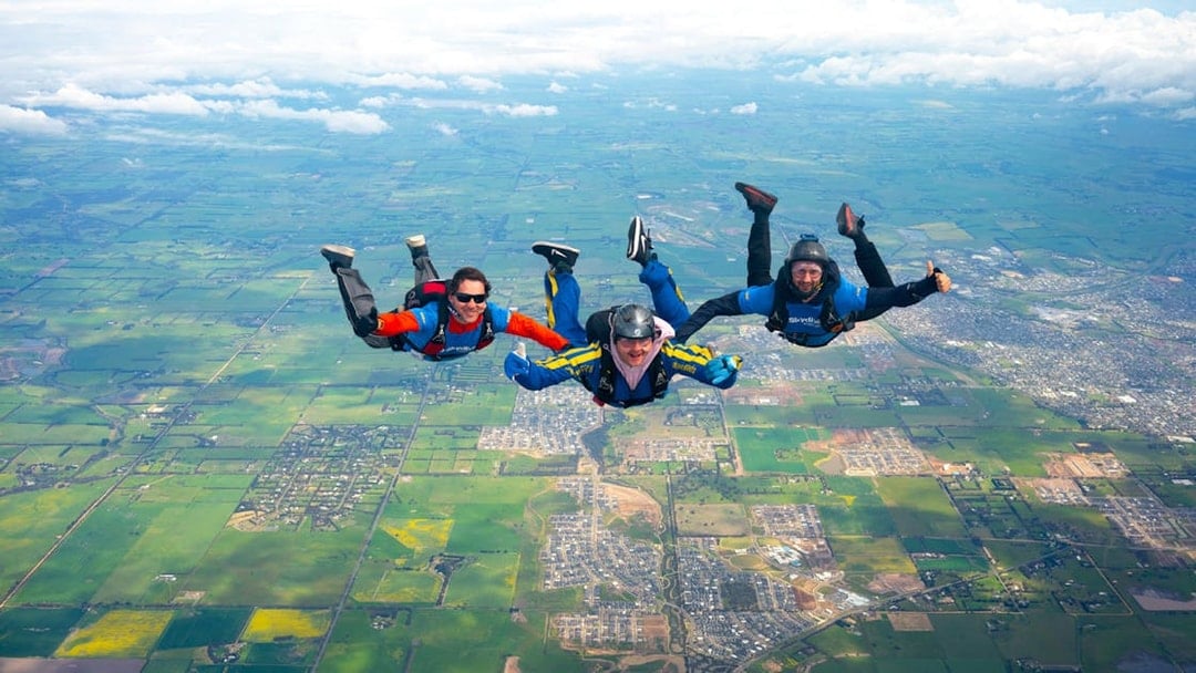 Skydivers in tandem freefall over Great Ocean Road, Australia.