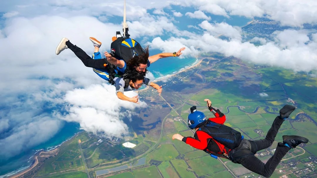 Skydivers tandem freefall over Great Ocean Road coastline, Australia.