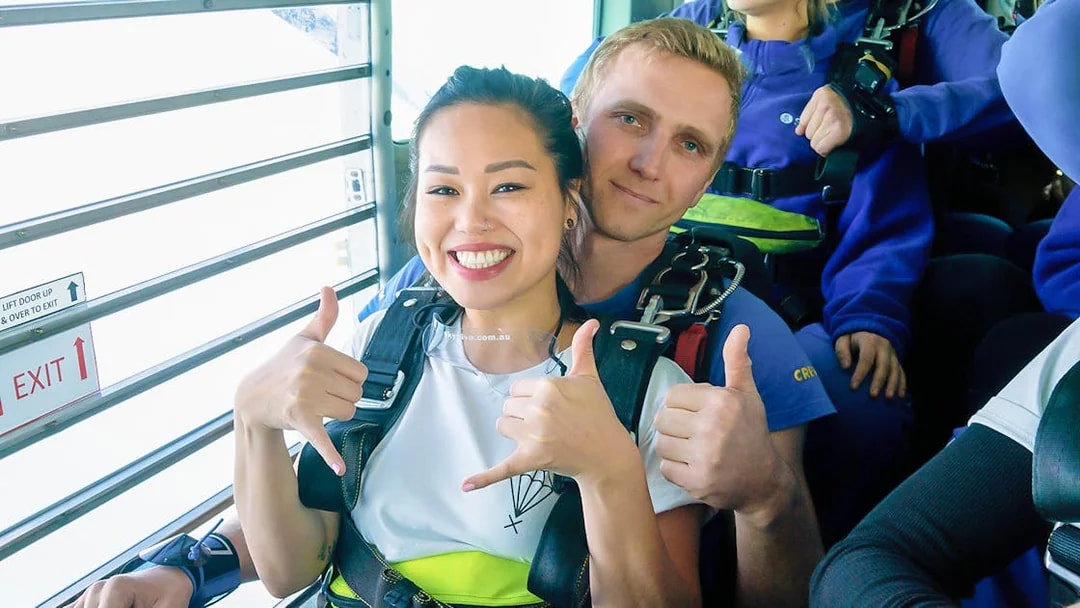 Tandem skydivers giving thumbs up before jumping over St Kilda Beach, Melbourne.
