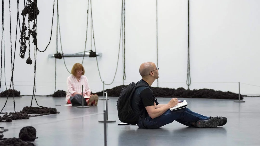 Visitors sketching art installations at Tate Modern, London.
