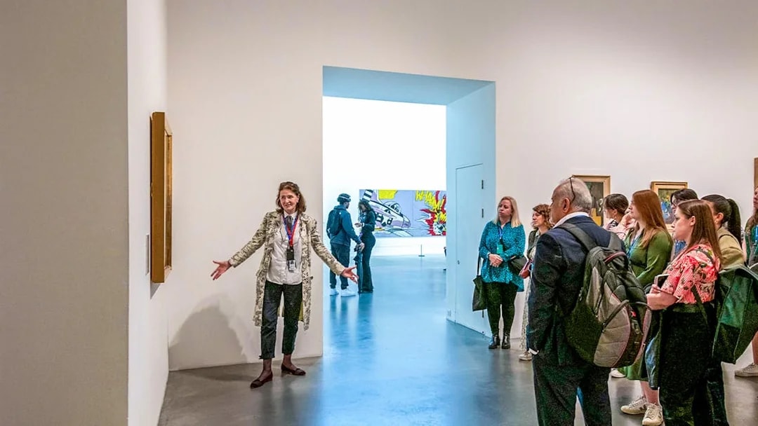 Guide explaining artwork to visitors inside Tate Modern.
