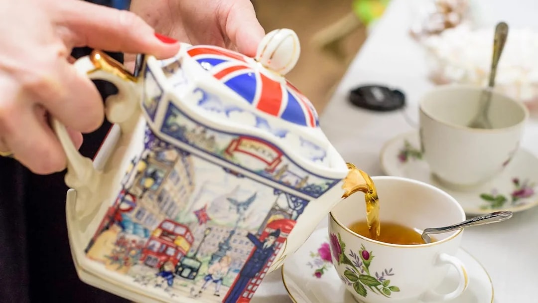 Pouring tea from a decorative teapot into a floral cup at Tate Modern Restaurant.