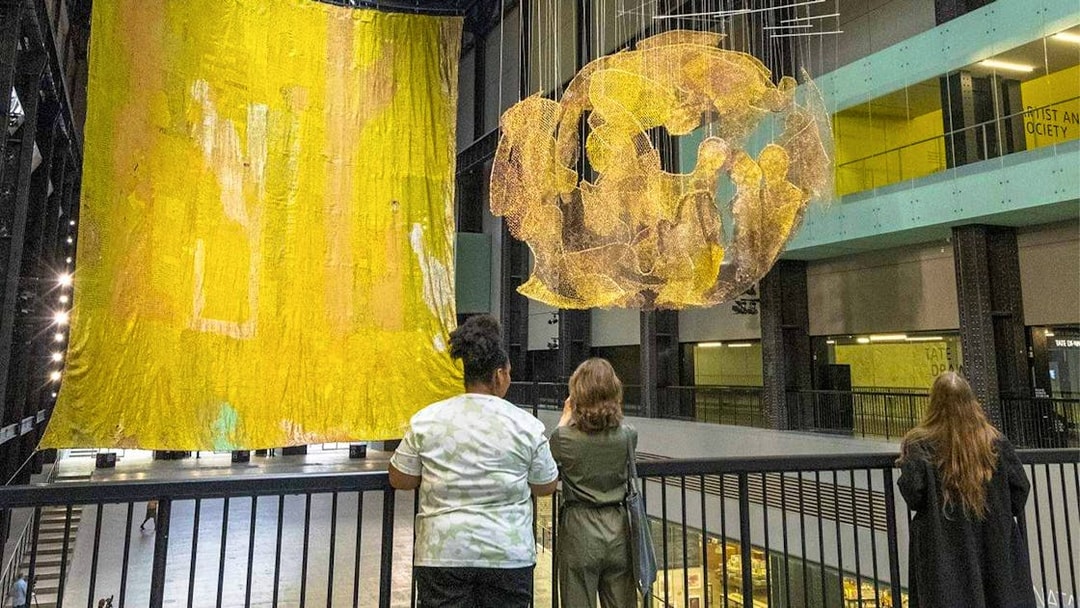 Visitors observing large art installations at Tate Modern, London.