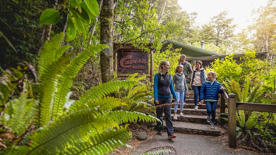 Visitors walking through lush greenery at Te Anau Glowworm Caves entrance.