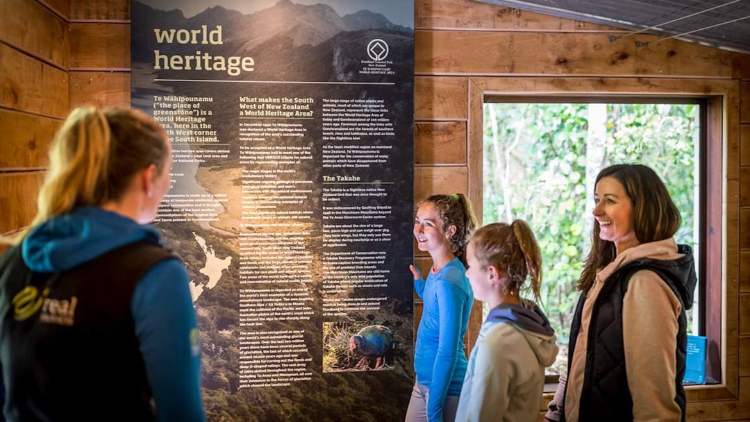 Visitors reading a World Heritage display at Te Anau Glowworm Caves, New Zealand.