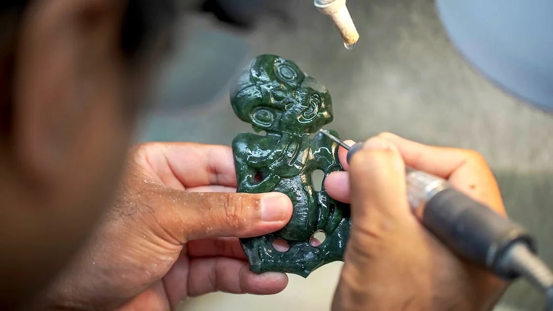 Carving a traditional Māori greenstone pendant at Te Puia, New Zealand.