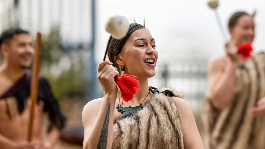 Performer in traditional Māori attire during Te Puia Haka experience, New Zealand.