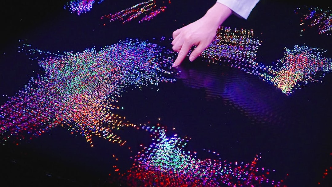Interactive digital art display at Team Lab Abu Dhabi with colorful lights and hand interaction.