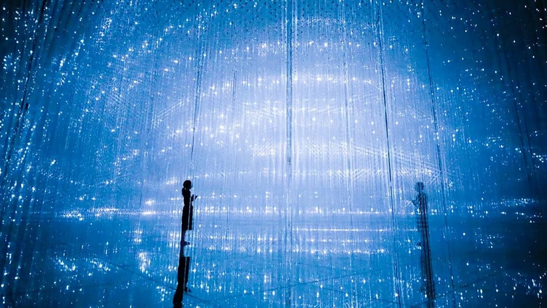 Visitors at TeamLab Planets Tokyo in a digital art installation with blue lights.