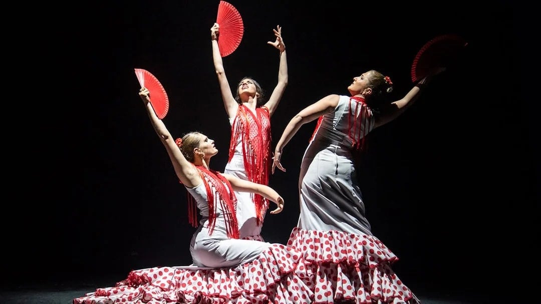 Flamenco dancers with red fans performing at Teatro Flamenco Barcelona.