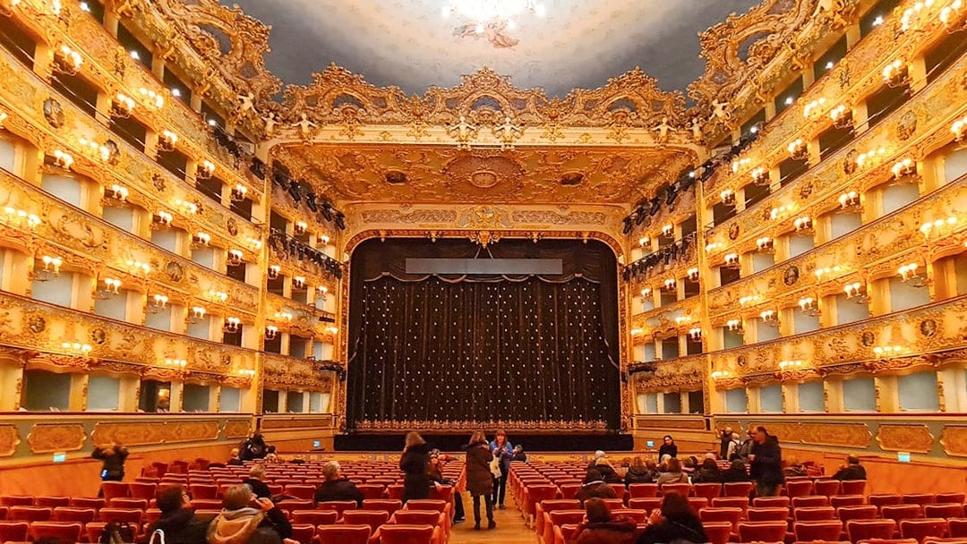 Teatro La Fenice interior with ornate balconies and stage curtain in Venice, Italy.