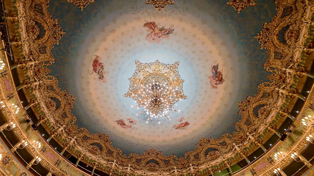 Teatro La Fenice ornate ceiling with chandelier, Venice opera house interior.