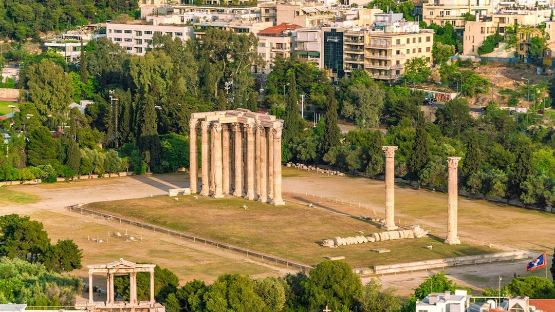 Temple of Olympian Zeus ruins in Athens with surrounding cityscape.