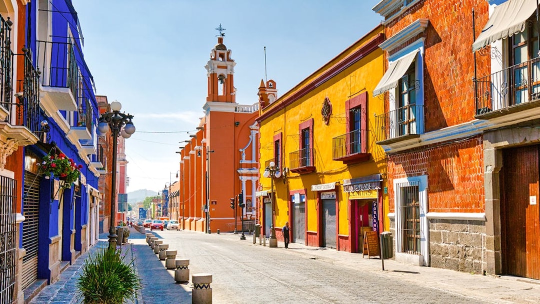 Colorful buildings along cobblestone street in historic Mexico City center.