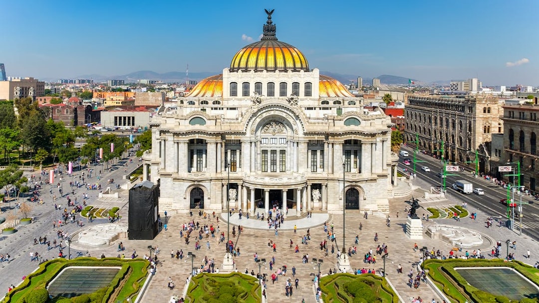 Palace of Fine Arts in Mexico City with people walking in the plaza.