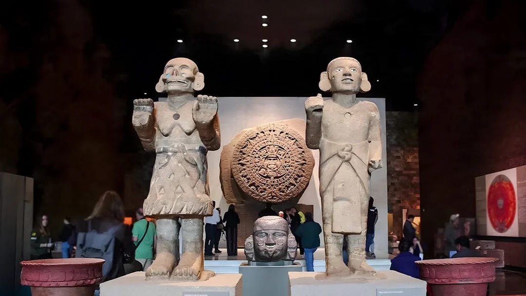 Visitors viewing ancient sculptures and the Aztec calendar stone at the Anthropology Museum, Mexico City.