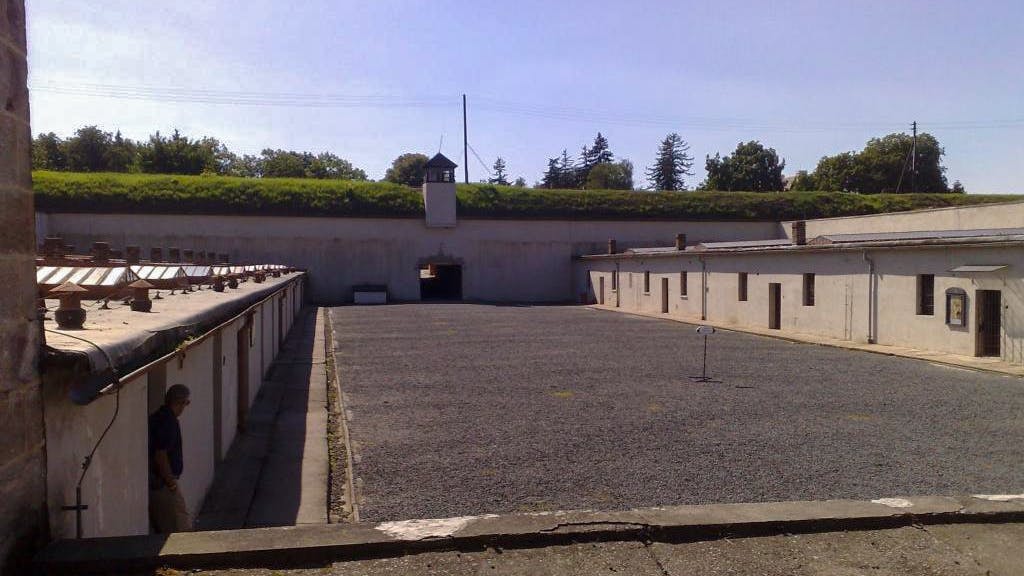 Terezin Concentration Camp courtyard with historical buildings and watchtower, part of a tour from Prague.