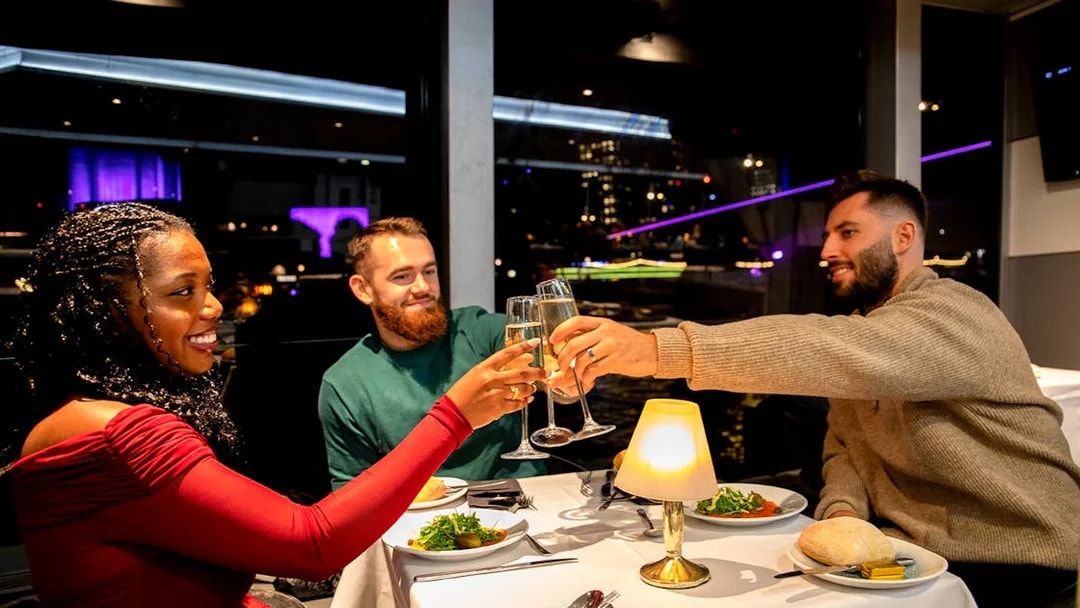 Guests toasting at a Christmas dinner on a Thames River cruise.