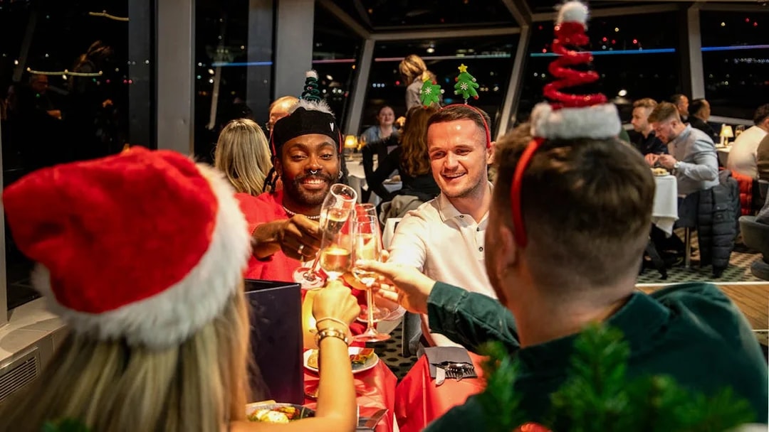 Guests toasting at Christmas dinner on Thames River cruise.
