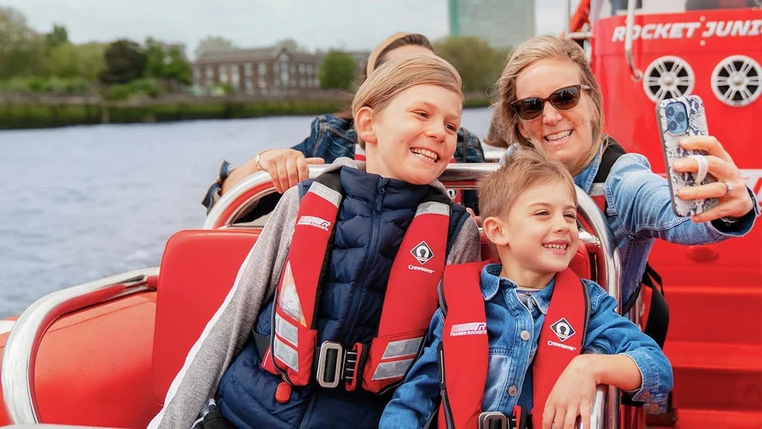 Family enjoying Thames speed boat ride, taking a selfie on the river.