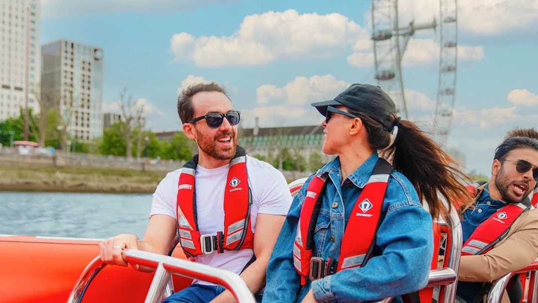 People enjoying a Thames speed boat ride with the London Eye in the background.
