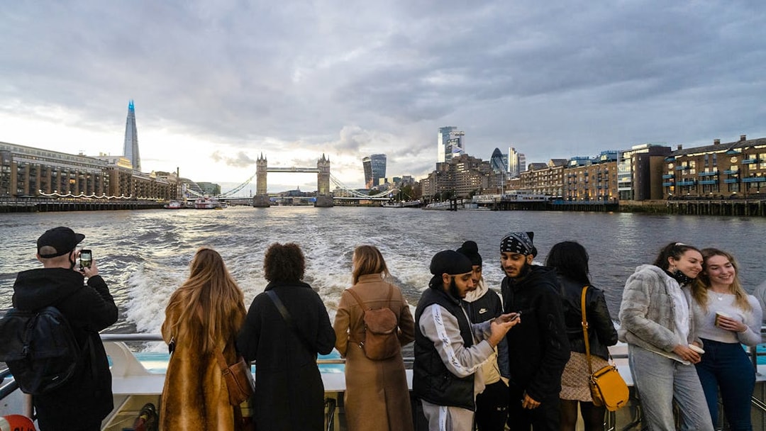 Passengers enjoying Thames River Uber Boat Tour with view of Tower Bridge and London skyline.