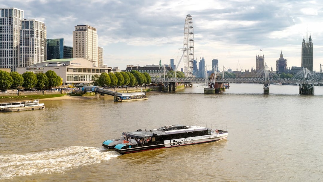 Uber Boat on Thames River with London Eye and Westminster in background.