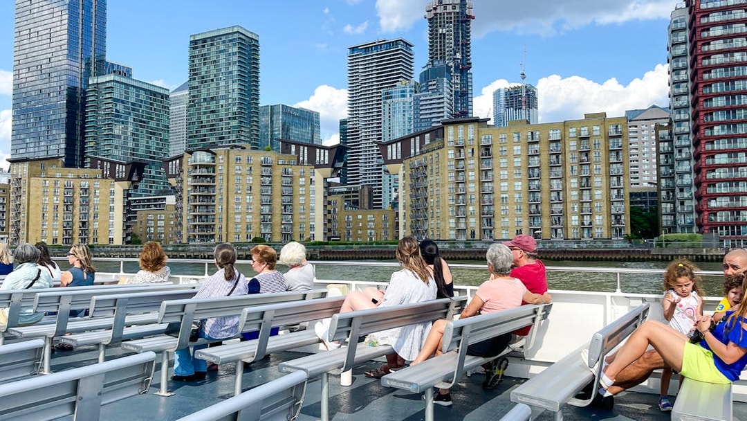 Passengers on a London sightseeing cruise view Canary Wharf skyline.