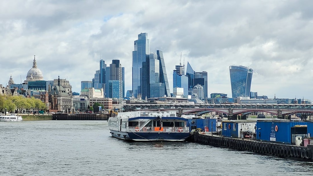 Cruise boat on the River Thames with London skyline, including St. Paul's Cathedral and modern skyscrapers.
