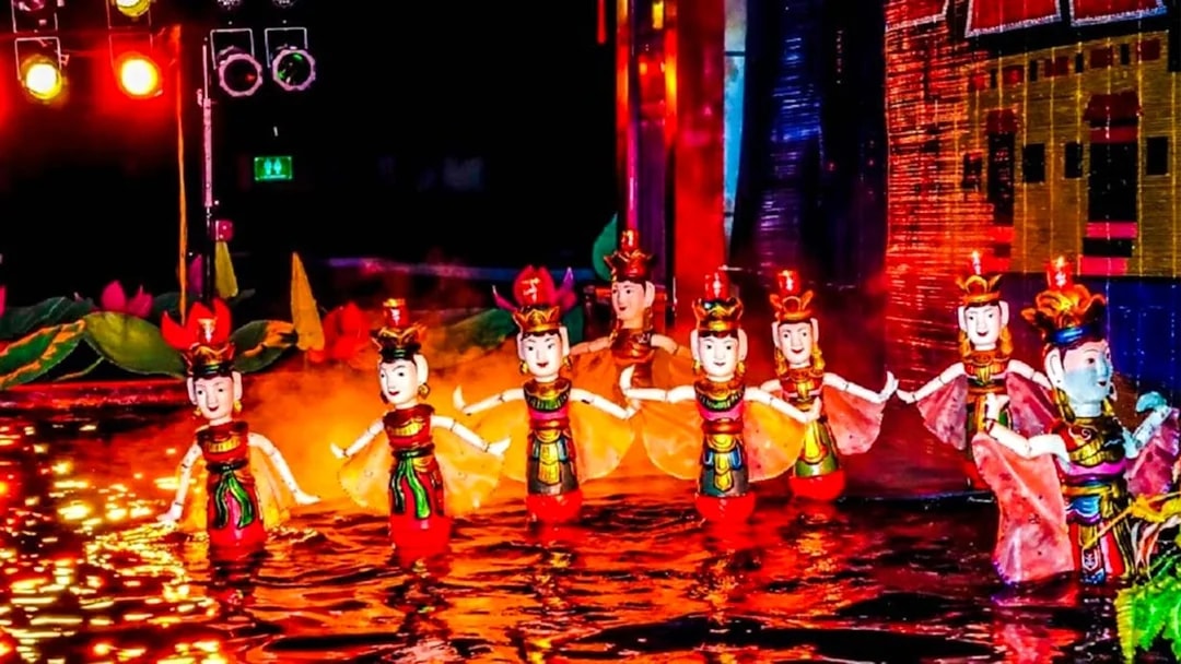 Female puppets in traditional attire perform at Thang Long Water Puppet Show, Hanoi, under red lights.